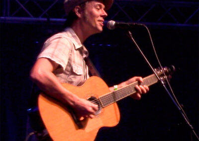 A man playing an acoustic guitar in front of a microphone, skillfully strumming blues music in Atlanta.